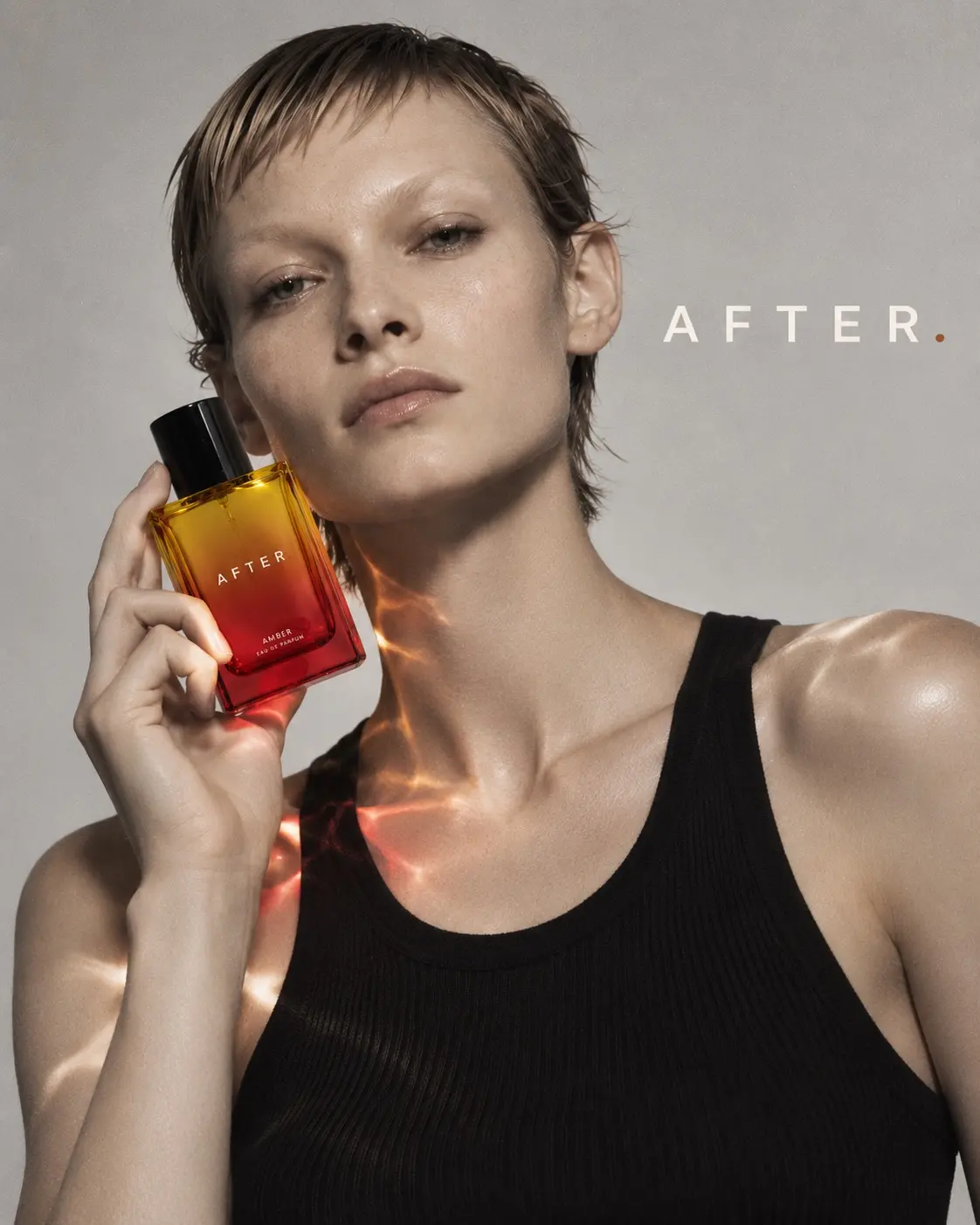 A model holding a red and amber AFTER. fragrance bottle